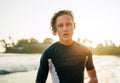 Portrait of a handsome teen boy surfing rashguard on the sand Indian ocean beach with sunset on background. Happy teen time and Royalty Free Stock Photo