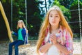 Portrait handsome teen pleading or beging at park. On the background other girl riding a swing