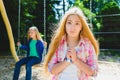 Portrait handsome teen pleading or beging at park. On the background other girl riding a swing