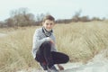 Portrait of handsome teenage boy sitting and smiling on white sand on Baltic sea beach Royalty Free Stock Photo