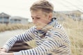 Portrait of handsome teenage boy sitting and smiling on white sand on Baltic sea beach Royalty Free Stock Photo