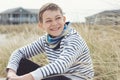 Portrait of handsome teenage boy sitting and smiling on white sand on Baltic sea beach Royalty Free Stock Photo