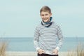 Portrait of handsome teenage boy sitting and smiling on white sand on Baltic sea beach Royalty Free Stock Photo