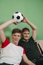 Teenage brothers sitting on couch with soccer ball