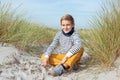 Portrait of handsome teenager boy sitting on white sand on beach of Baltic sea Royalty Free Stock Photo