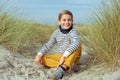 Portrait of handsome teenager boy sitting on white sand on beach of Baltic sea Royalty Free Stock Photo