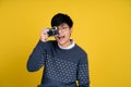 Portrait of a handsome tomboy looking good. Asian woman with short hair on yellow background. She is taking pictures, isolated