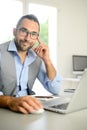 Portrait of handsome trendy casual mid age business man in office desk with laptop computer Royalty Free Stock Photo