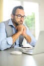 Portrait of handsome trendy casual mid age business man in office desk with laptop computer Royalty Free Stock Photo