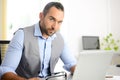 Portrait of handsome trendy casual mid age business man in office desk with laptop computer Royalty Free Stock Photo