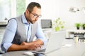 Portrait of handsome trendy casual mid age business man in office desk with laptop computer Royalty Free Stock Photo