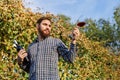 Portrait of handsome wine maker holding in his hand bottle and a glass of red wine and tasting it, checking wine quality while Royalty Free Stock Photo