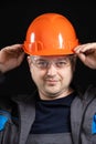 Portrait of a handsome worker builder in overalls, helmet and glasses on a black background. Royalty Free Stock Photo
