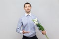 Handsome man standing with bouquet of flowers, showing beautiful plants, gift for anniversary. Royalty Free Stock Photo