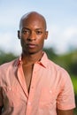 Portrait handsome young African American male model looking at camera. Bald man wearing a pink button shirt on blurry