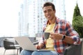 Portrait of handsome young African-American man with laptop and cup of drink in cafe Royalty Free Stock Photo