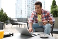 Portrait of handsome young African-American man with laptop and cup of drink in cafe Royalty Free Stock Photo