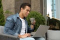 Portrait of handsome young African-American man with laptop and cup of drink in cafe Royalty Free Stock Photo