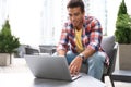 Portrait of handsome young African-American man with laptop in cafe Royalty Free Stock Photo