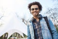 Portrait of handsome young african-american student with afro hairstyle smiling at camera, wearing denim coat and Royalty Free Stock Photo