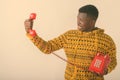 Studio shot of young angry black African man looking at old telephone against white background Royalty Free Stock Photo