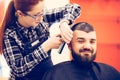 Portrait of handsome young bearded caucasian man getting trendy haircut in modern barber shop. Royalty Free Stock Photo