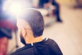 Portrait of handsome young bearded caucasian man getting trendy haircut in modern barber shop. Royalty Free Stock Photo