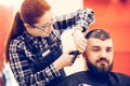 Portrait of handsome young bearded caucasian man getting trendy haircut in modern barber shop. Royalty Free Stock Photo