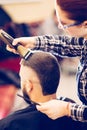 Portrait of handsome young bearded caucasian man getting trendy haircut in modern barber shop. Royalty Free Stock Photo