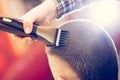 Portrait of handsome young bearded caucasian man getting trendy haircut in modern barber shop. Royalty Free Stock Photo