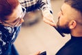 Portrait of handsome young bearded caucasian man getting trendy haircut in modern barber shop. Royalty Free Stock Photo