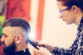 Portrait of handsome young bearded caucasian man getting trendy haircut in modern barber shop. Royalty Free Stock Photo