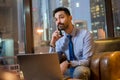 Portrait of handsome young business man with laptop talking on mobile phone in modern office. Royalty Free Stock Photo