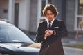 Portrait of handsome young businessman in black suit and tie outdoors near modern car in the city Royalty Free Stock Photo