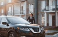 Portrait of handsome young businessman in black suit and tie outdoors near modern car in the city Royalty Free Stock Photo