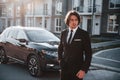 Portrait of handsome young businessman in black suit and tie outdoors near modern car in the city Royalty Free Stock Photo