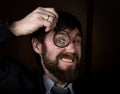 Portrait of handsome young businessman looking through magnifying glass on a brown background Royalty Free Stock Photo