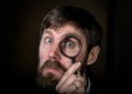 Portrait of handsome young businessman looking through magnifying glass on a brown background Royalty Free Stock Photo