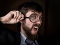 Portrait of handsome young businessman looking through magnifying glass on a brown background Royalty Free Stock Photo