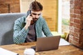 Portrait of handsome young businessman sitting at desk with laptop and talking on mobile phone. Communication concept Royalty Free Stock Photo