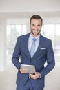 Portrait of handsome young businessman standing with digital tablet in new office Royalty Free Stock Photo
