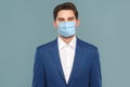 Portrait of handsome young businessman with surgical medical mask looking at camera Royalty Free Stock Photo