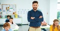 Portrait of handsome young Caucasian male tutor standing in classroom looking at camera and smiling. Children using Royalty Free Stock Photo