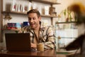 Portrait of handsome young digital nomad, man working in cafe on laptop, looking happy and pleased with his online Royalty Free Stock Photo