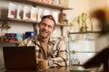 Portrait of handsome young digital nomad, man working in cafe on laptop, looking happy and pleased with his online Royalty Free Stock Photo