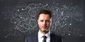 Portrait of handsome young european businessman on chalkboard wall background with arrows and thought icons sketch. Solution,