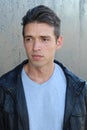 Portrait of a handsome young fashion man leaning on a gray wall while looking away from the camera Royalty Free Stock Photo