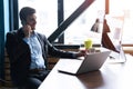 Portrait of handsome young male sitting at office desk with laptop computer and talking on mobile phone. Communication Royalty Free Stock Photo