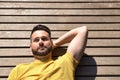 Portrait of handsome young man, with blue eyes and wearing yellow t-shirt, lying on a wooden slatted surface with thoughtful Royalty Free Stock Photo