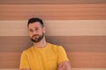 Portrait of handsome young man, with blue eyes and yellow shirt, with his arms crossed and his head leaning against a wall very Royalty Free Stock Photo